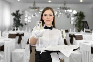 Close-up of a champagne glass in the hands of a waiter sommelier