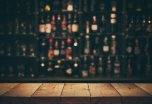 Empty the top of wooden table with blurred counter bar and bottles Background /for your product display